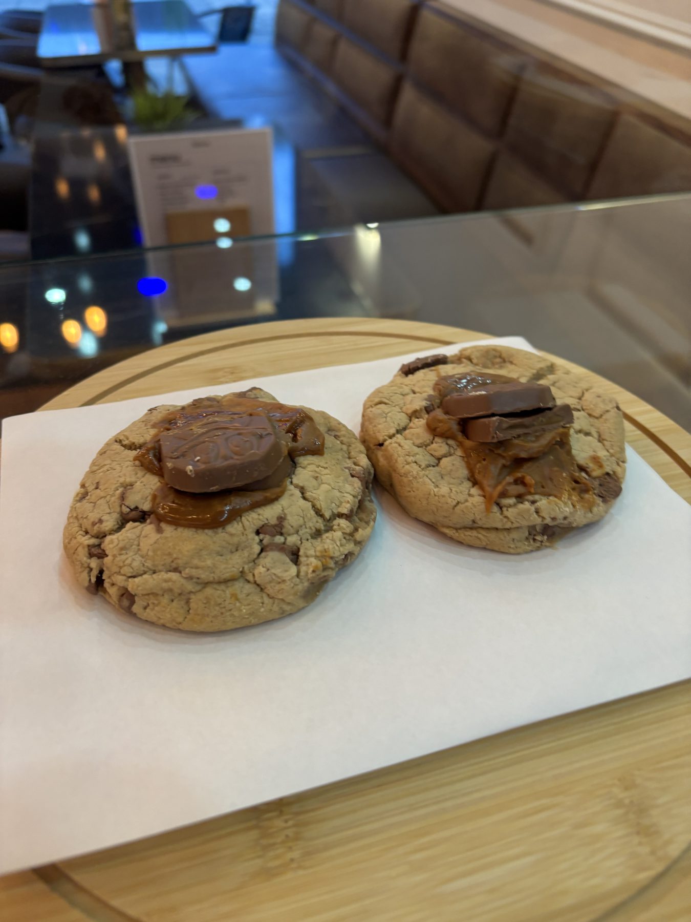 Chocolate chip cookies with caramel and chocolate pieces on a wooden tray.