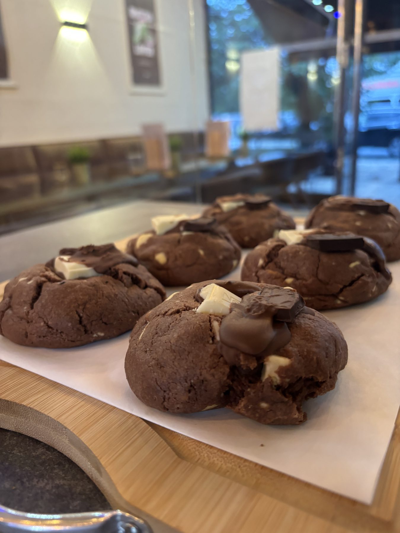 Double chocolate cookies with white chocolate chunks on a wooden tray.
