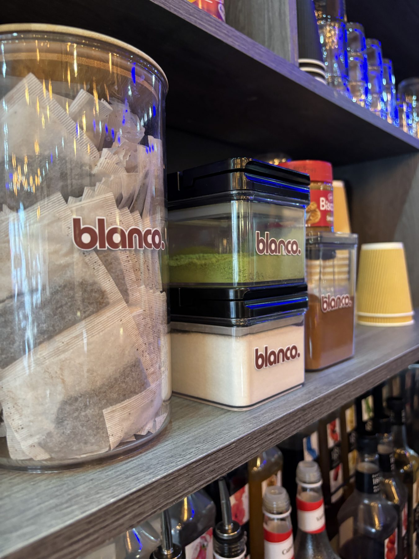 Blanco-branded jars of tea, sugar, and matcha on the bar shelf.