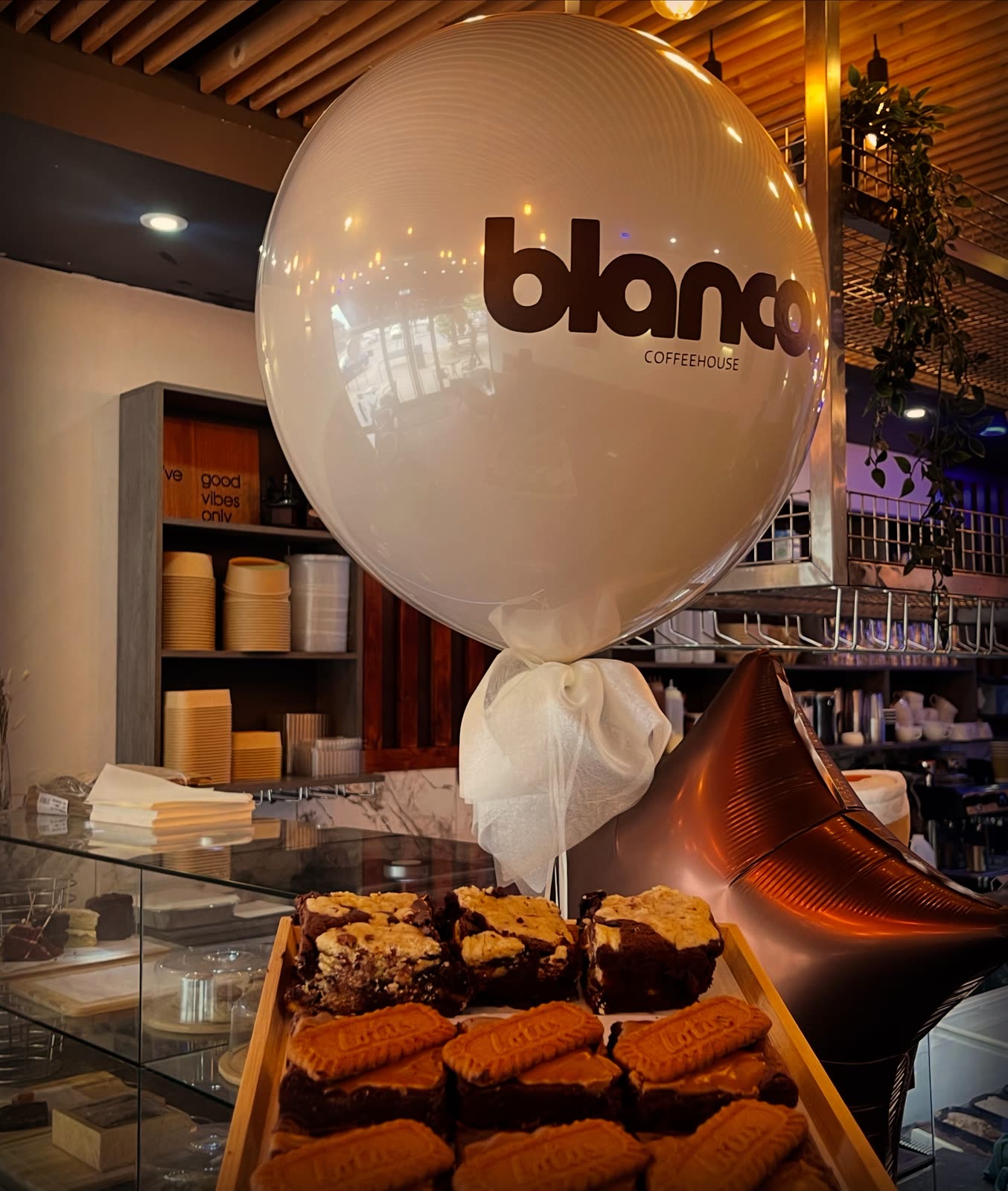 Inside Blanco Coffee House: a branded balloon above a tray of brownies.