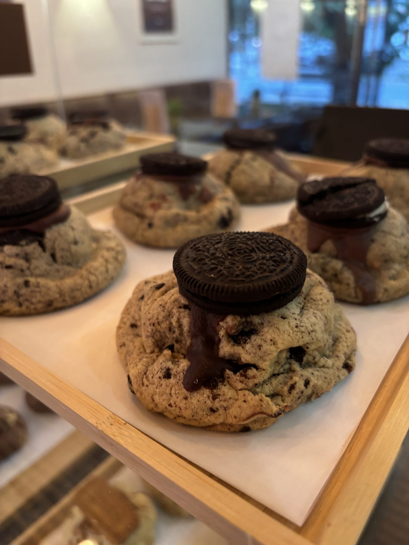 Oreo cookies with a chocolate drip on a wooden tray.